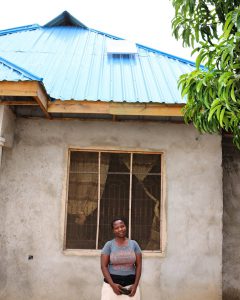 A. Kagaruki in front of her house with SHS. Image by Carmen Rosa