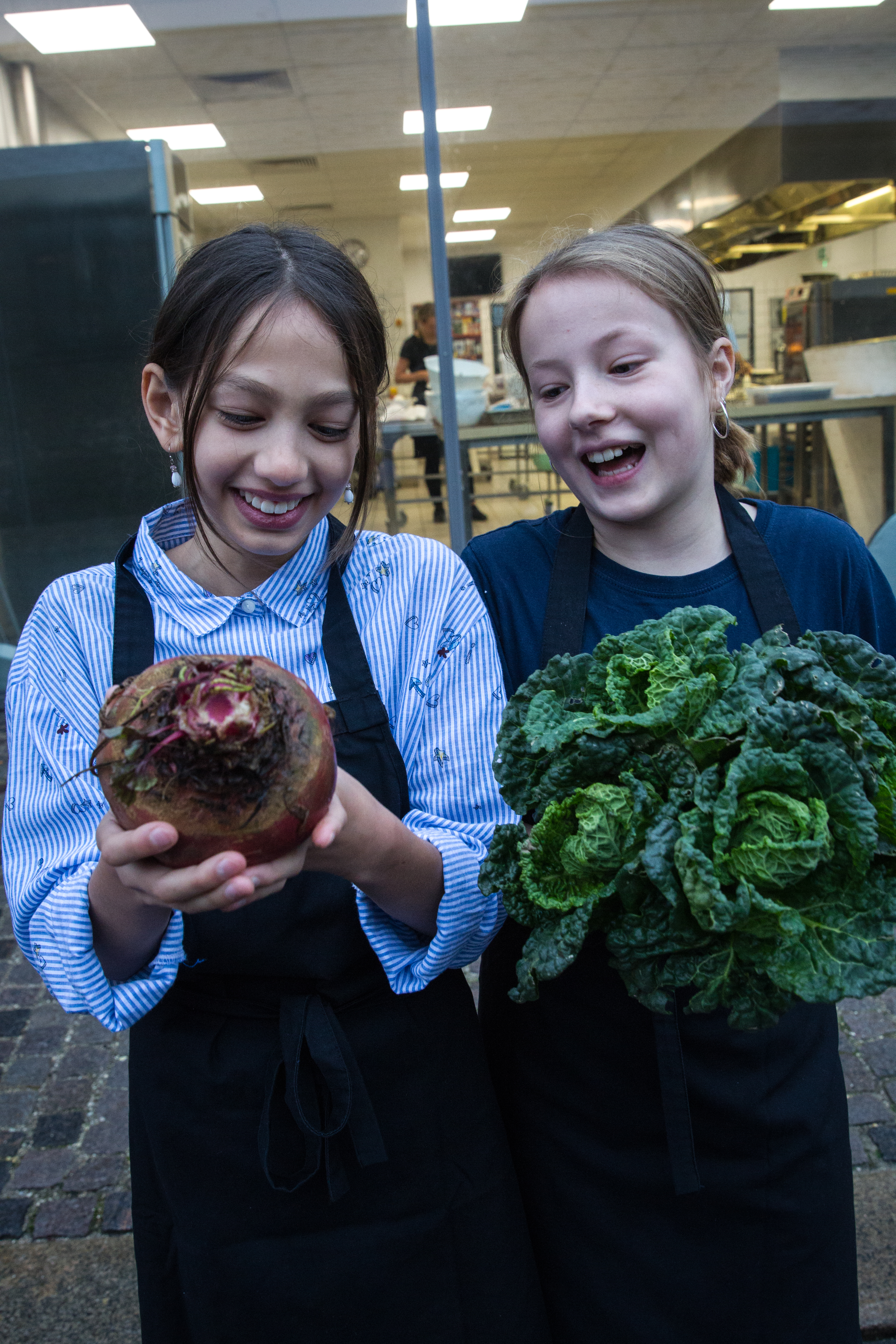 two girls holding vegetables